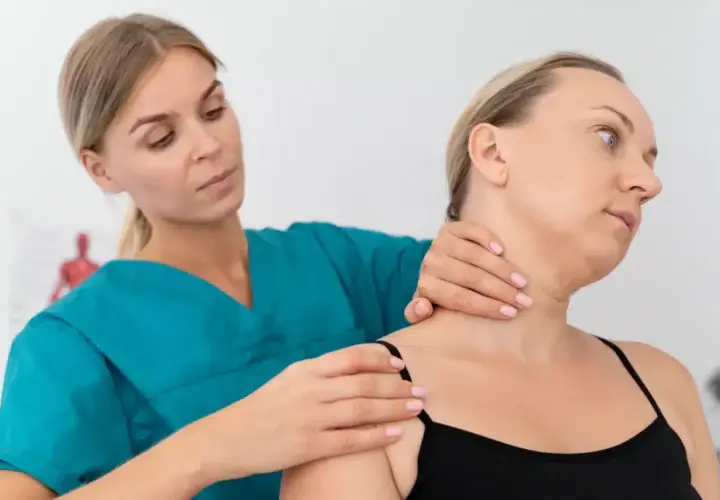 Fizjoterapeuta bada szyję pacjentki, oceniając potencjalne objawy chorobowe kręgosłupa szyjnego.