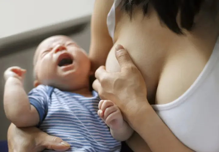 Bébé pleure pendant l'allaitement, possible signe de mastite infectieuse.