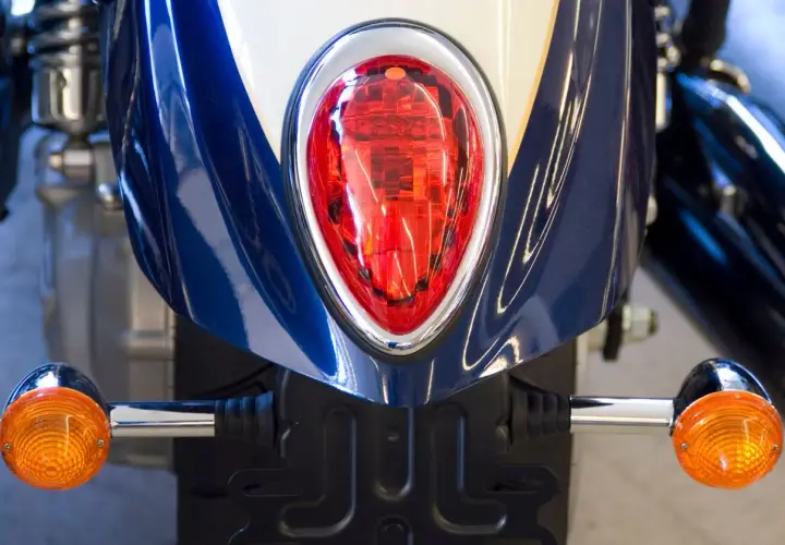 Detalle de moto azul con luces LED naranjas y piloto trasero rojo. Podría ser una multa por llevar luces LED en moto.