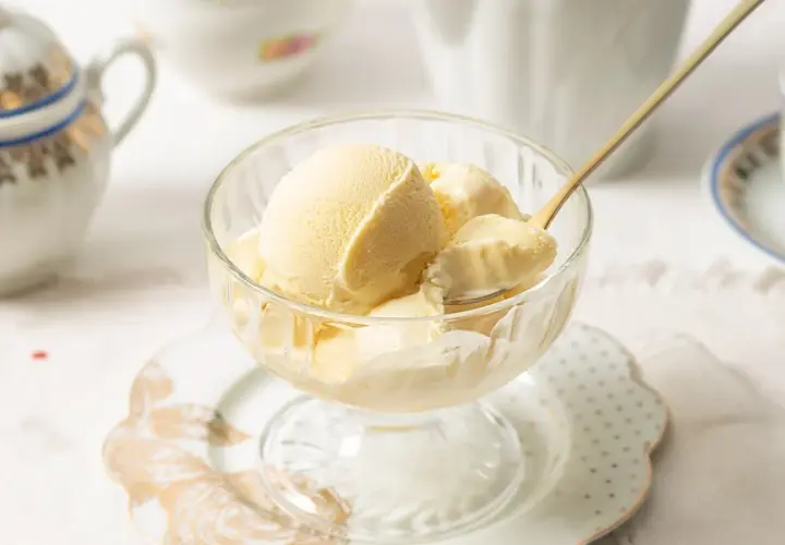 Copa de cristal con helado de mantecado cremoso, servido con una cuchara dorada.