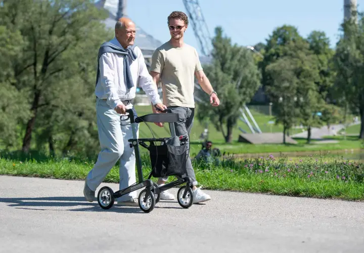 Ein älterer Mann geht mit einem Rollator spazieren, der ihm Halt gibt. Es gibt verschiedene Gehhilfen, die Mobilität im Alter unterstützen.
