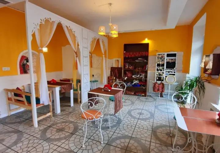 Wnętrze restauracji Samsara w Opolu, z żółtymi ścianami, białymi zdobieniami i stolikami. Idealne miejsce, by zapoznać się z ich menu.