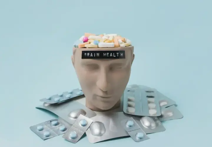 Testa di manichino piena di pillole, con la scritta "BRAIN HEALTH". Intorno, blister di psicofarmaci, suggerendo che il neurologo può prescrivere psicofarmaci.