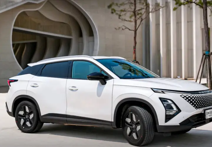 Biały OMODA hybryda zaparkowany przed nowoczesnym budynkiem. Stylowy SUV z charakterystycznym grillem i dynamiczną linią nadwozia.
