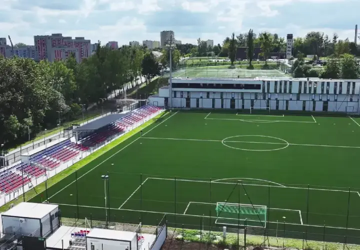 Nowy stadion Polonii Bytom z zieloną murawą, trybunami w kolorach czerwonym i niebieskim oraz nowoczesnym budynkiem klubowym.