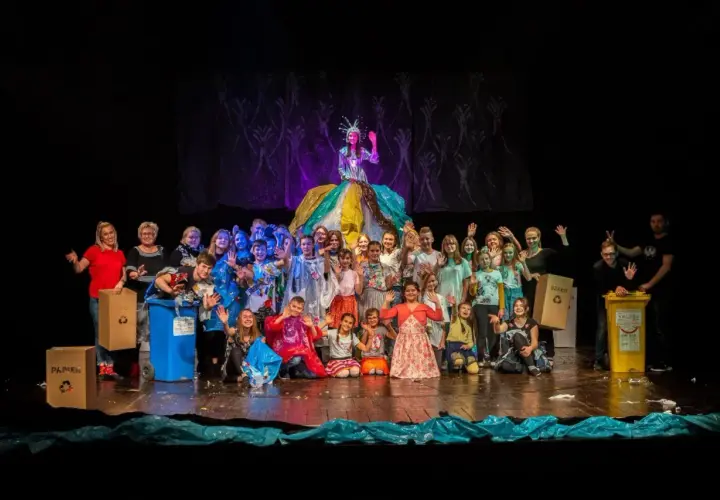 Uczestnicy studia teatralnego Gorzów pozują na scenie z kolorowymi strojami i koszami do segregacji śmieci.