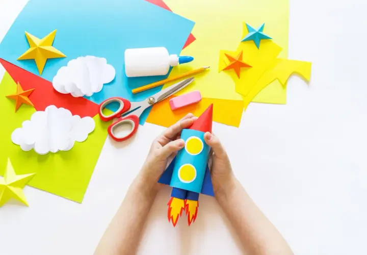 Kinder basteln einen Raketen-Weltraumflug. Alles für bastelkleber selber machen liegt bereit: Papier, Schere, Kleber, Stift.