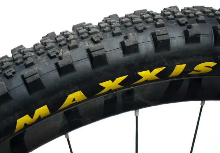 Close-up of a Maxxis Minion SS tire, showing its aggressive tread pattern and yellow branding. Ready for any trail.