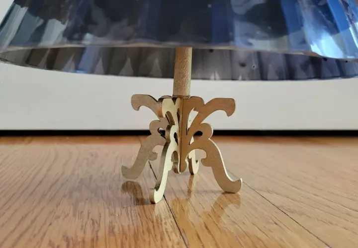 Base de un maniquí 3d de madera con un soporte ornamental, sosteniendo una falda de tela brillante.