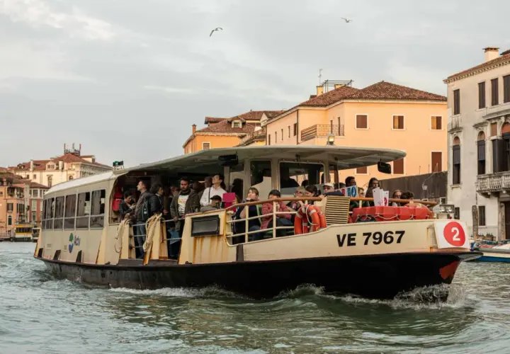 Un passager sur un vaporetto à Venise, naviguant sur les canaux bordés de bâtiments historiques.