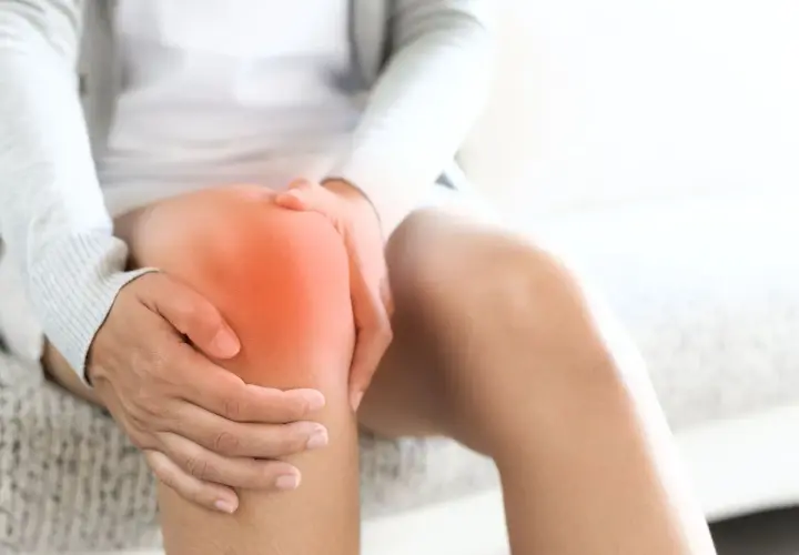 Person hält schmerzendes Knie, das rot leuchtet. Richtige Schuhe können bei Knieschmerzen helfen.