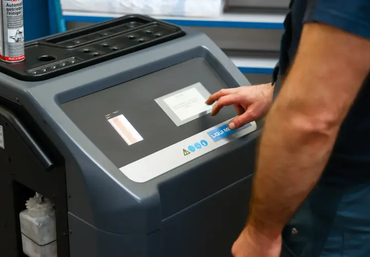 Mechanik dotyka ekranu maszyny do adaptacji skrzyni biegów, przygotowując ją do czyszczenia.