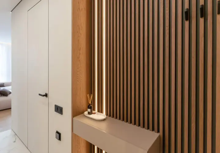 Drewniane lamele i subtelne podświetlenie tworzą tani pomysł na ścianę. Minimalistyczna konsola z dyfuzorem dodaje elegancji.
