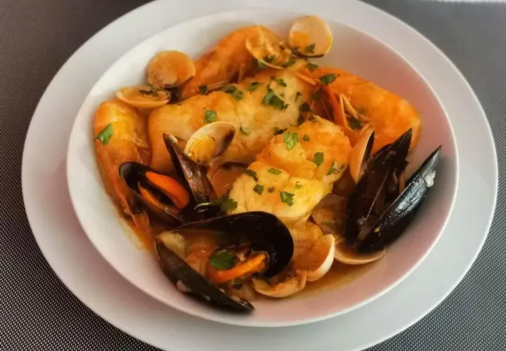 Caldereta de pescado con gambas, mejillones y almejas, todo ello espolvoreado con perejil fresco.