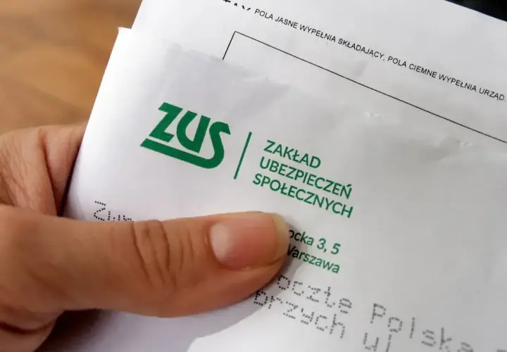 Dłoń trzyma dokument ZUS. Rozważasz umowę o dzieło i jej podatek? ZUS wyjaśnia zasady.