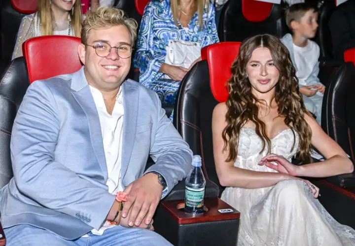 Roksana Węgiel i jej mąż, Kevin Mglej, siedzą w kinie. Ona w białej sukni, on w błękitnej marynarce.