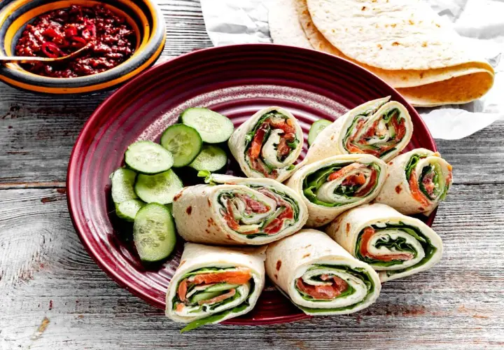 Pyszna tortilla z łososiem, serkiem i świeżym ogórkiem, podana z pikantnym sosem. Idealna na szybki lunch.