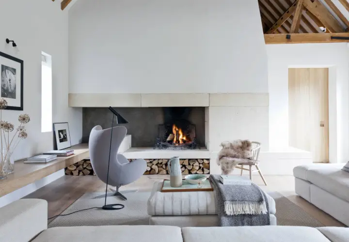 Acogedor salón con un mueble con chimenea encendida, sillón gris, sofás y decoración rústica.