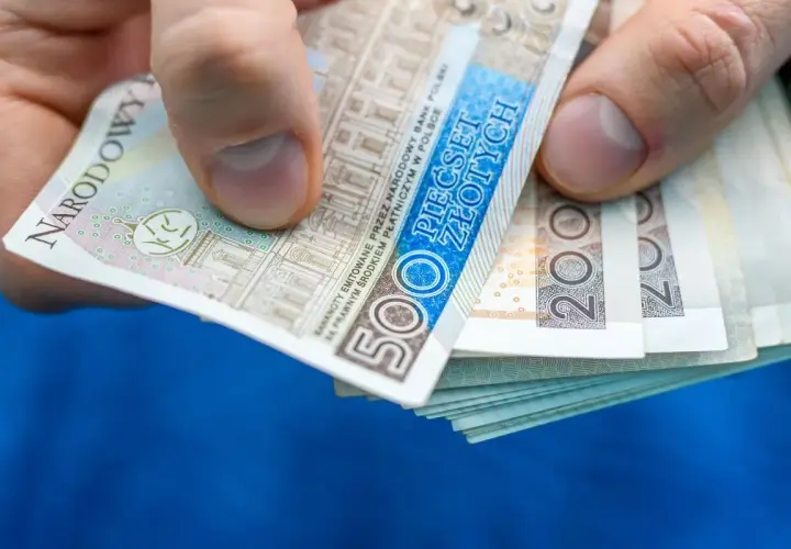 Dłoń trzyma stos banknotów 500 zł i 200 zł. Może to być zapłata za rachunek, np. taryfa urzędowa Energa.