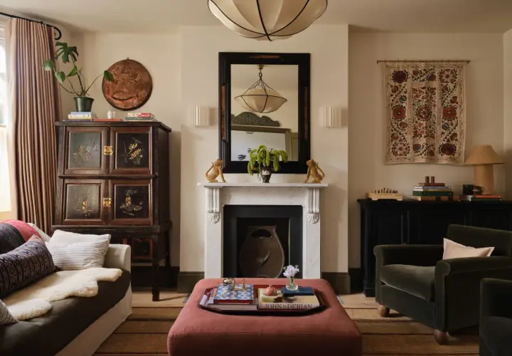 A living room with a fireplace, antique cabinet, and plush seating, showcasing a beautiful simplicity interior design.