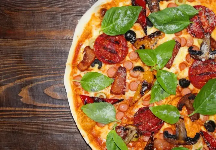 Pyszne rodzaje pizzy: z kiełbaską, boczkiem, pomidorami, oliwkami i bazylią na drewnianym tle.