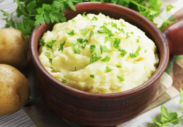 Un cremoso puré de patatas, un acompañamiento perfecto, adornado con perejil fresco.
