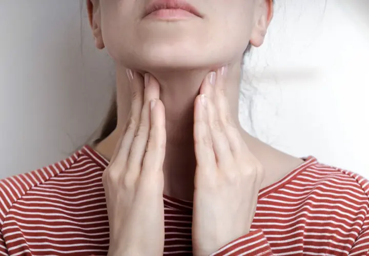 Femme touchant sa gorge, possible symptôme mononucléose. Douleur ou gonflement au cou.
