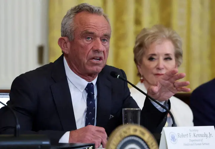 Robert F. Kennedy Jr. przemawia przy mikrofonie, obok siedzi kobieta.