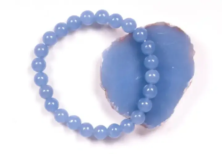 Armband aus hellblauen Perlen, die auf einem Stück Angelit Stein liegen.