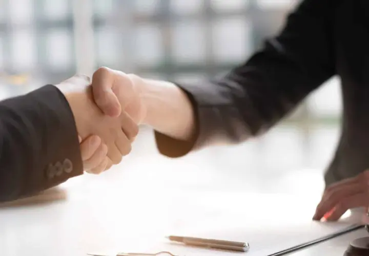 Poignée de main entre deux avocats, symbolisant un accord ou un **départage prudhomme**. Un maillet de juge est visible sur la table.