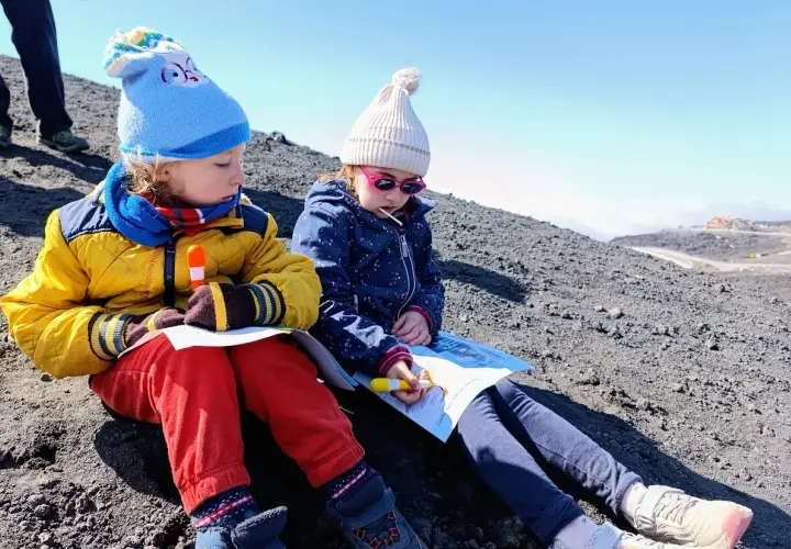 Bambini vestiti a strati, con cappelli e giacche, imparano come vestirsi per andare sull'Etna.