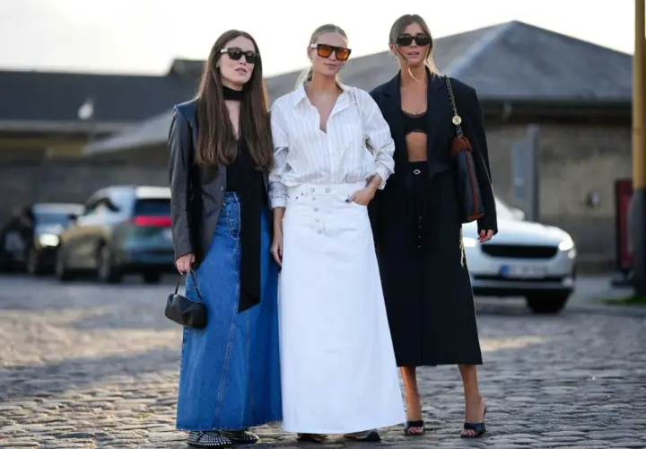 Trzy kobiety prezentują, jakie spódnice są teraz modne: dżinsowa maxi, biała maxi i czarna maxi.