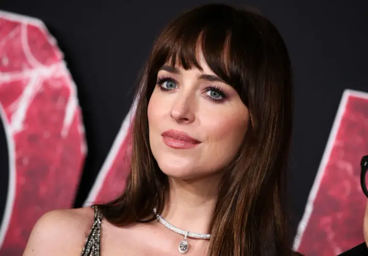 Dakota Johnson con un flequillo abierto y ojos azules intensos, luciendo un collar de diamantes.