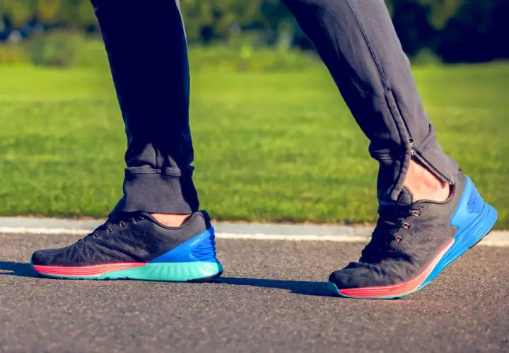 Biegacz stawia stopę, obserwując supinację. Kolorowe buty sportowe na bieżni.
