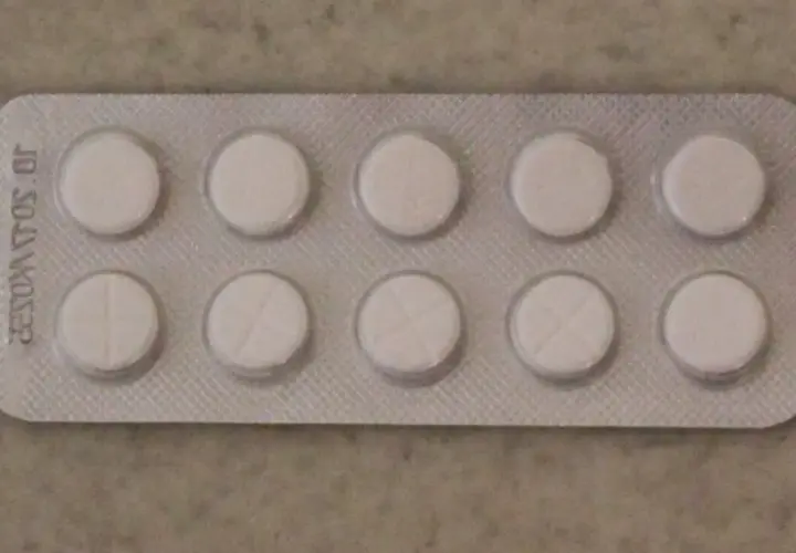 Opakowanie z dziesięcioma białymi tabletkami, niektóre z nacięciem. Może to być lek na receptę, np. tizagelan.