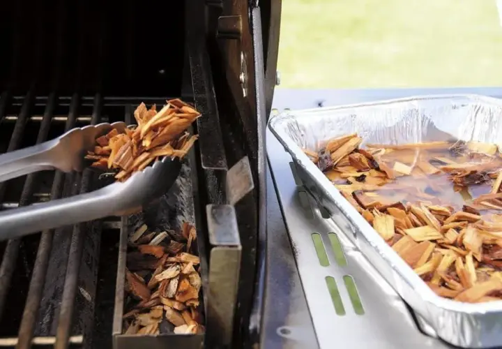 Des copeaux de bois sont placés dans un fumoir pour barbecue Weber. Une autre partie est trempée dans l'eau.