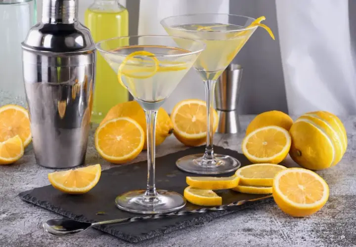 Dwa kieliszki z martini, cytryny i shaker. Idealne na orzeźwiający drink.