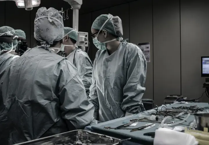 Chirurghi in sala operatoria discutono. Quanto guadagna un medico legale al mese? La risposta è complessa, ma il loro lavoro è fondamentale.