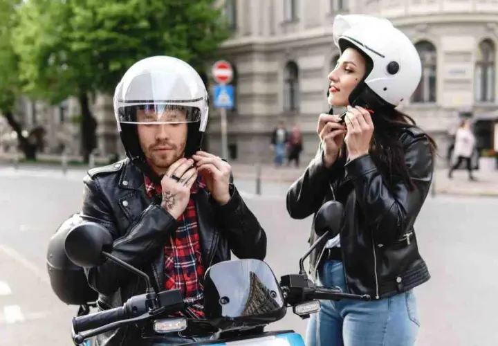 Coppia in moto, lui sistema il suo casco nuovo che fa male, lei il suo.