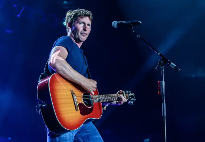 James Blunt na koncercie, grając na gitarze. W tle mikrofon, przypominający o jego hicie "You're Beautiful".
