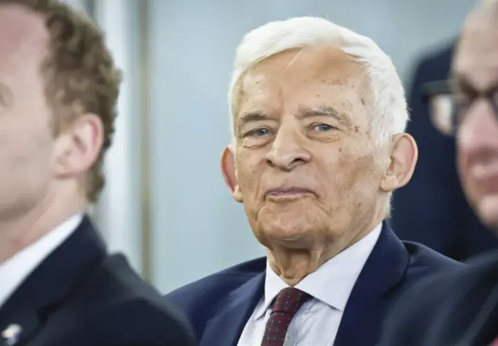 Jerzy Buzek, w otoczeniu innych mężczyzn, z uwagą słucha przemówienia.