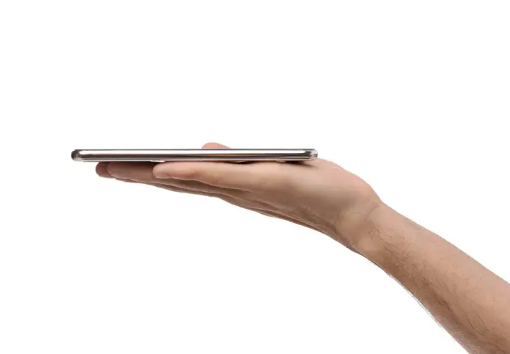 Dłoń trzyma cienki, srebrny smartfon. Może to być nowy model, np. kierunkowy 95 Polska.