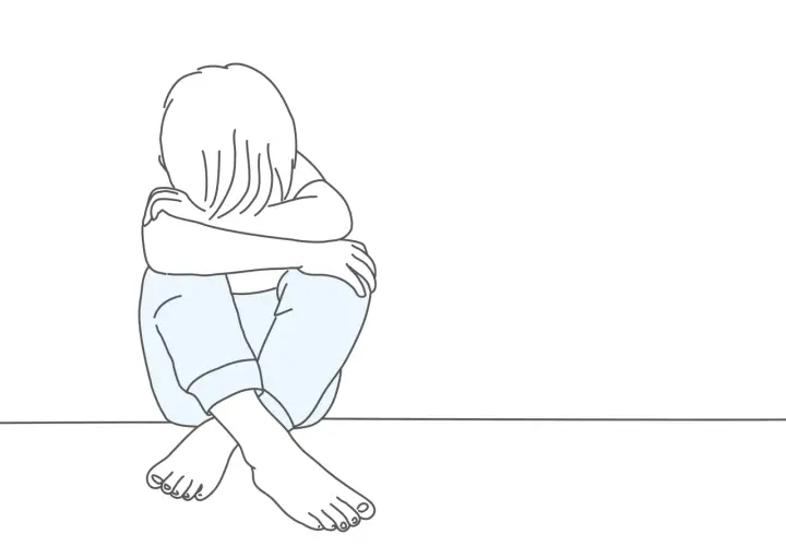Smutne dziecko skulone na podłodze. Psychologia oceniająca innych często prowadzi do poczucia izolacji i smutku.