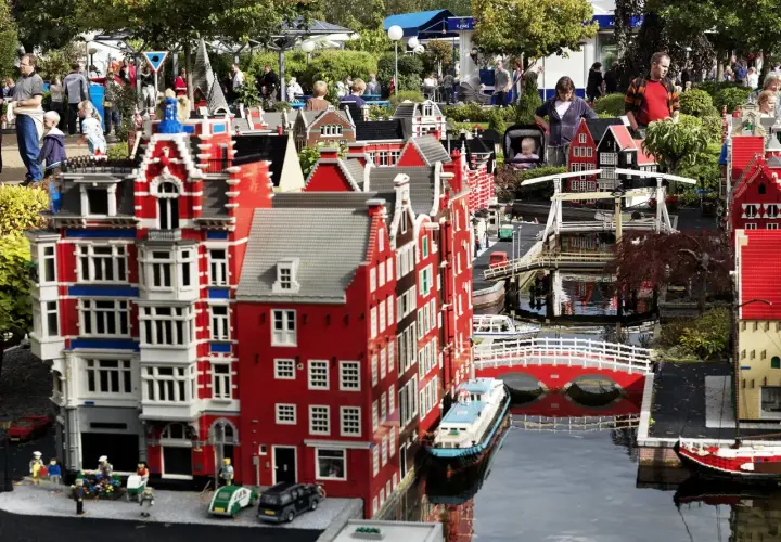 Miniaturowa holenderska zabudowa z kanałami i mostami w **Lego Land**. Ludzie spacerują wśród kolorowych budynków z klocków.