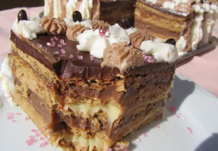 Tarta de galletas de la abuela de toda la vida, con capas de crema y chocolate, decorada con nata y granillo rosa.