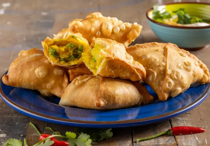 Samosa al forno dorati e croccanti, ripieni di verdure speziate. Un contorno piccante con peperoncino e coriandolo.