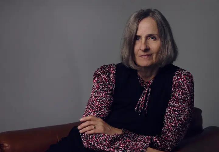Susanna Alakoski, en svensk författare, sitter på en brun soffa med armarna korslagda.