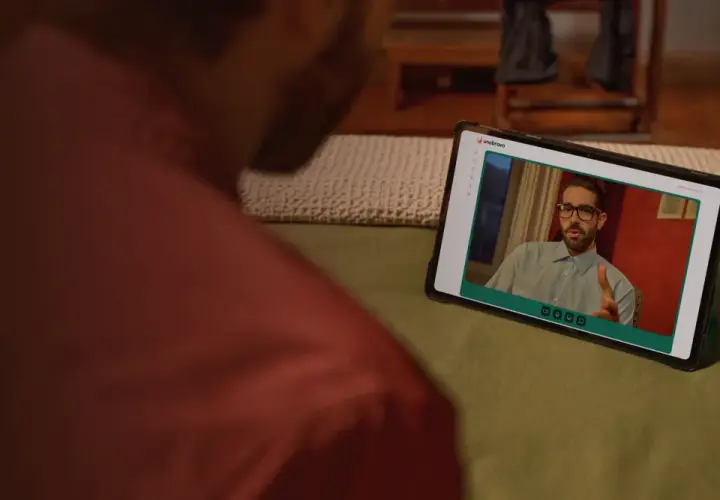 Uomo guarda un video su tablet. Sullo schermo, un uomo con occhiali parla, forse dando uno bravo recensioni.