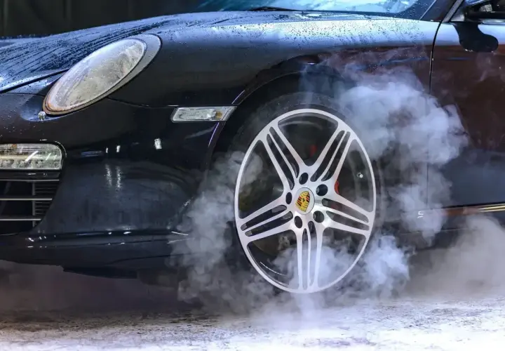 Czarny Porsche z dymem unoszącym się z koła. Zastanawiasz się, ozonowanie samochodu ile czasu zajmuje?