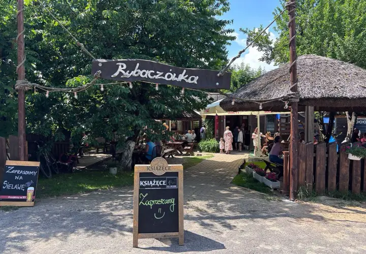 Rybaczówka zaprasza na sielawę. Letni ogródek z drewnianymi stołami i strzechą zachęca do odpoczynku.